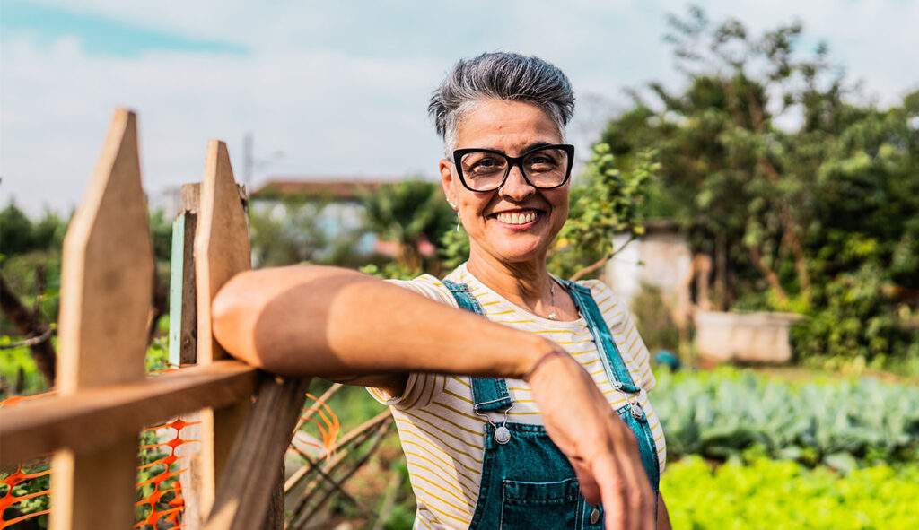 Woman standing confidently in her garden, symbolising security, steady growth, and long-term planning.